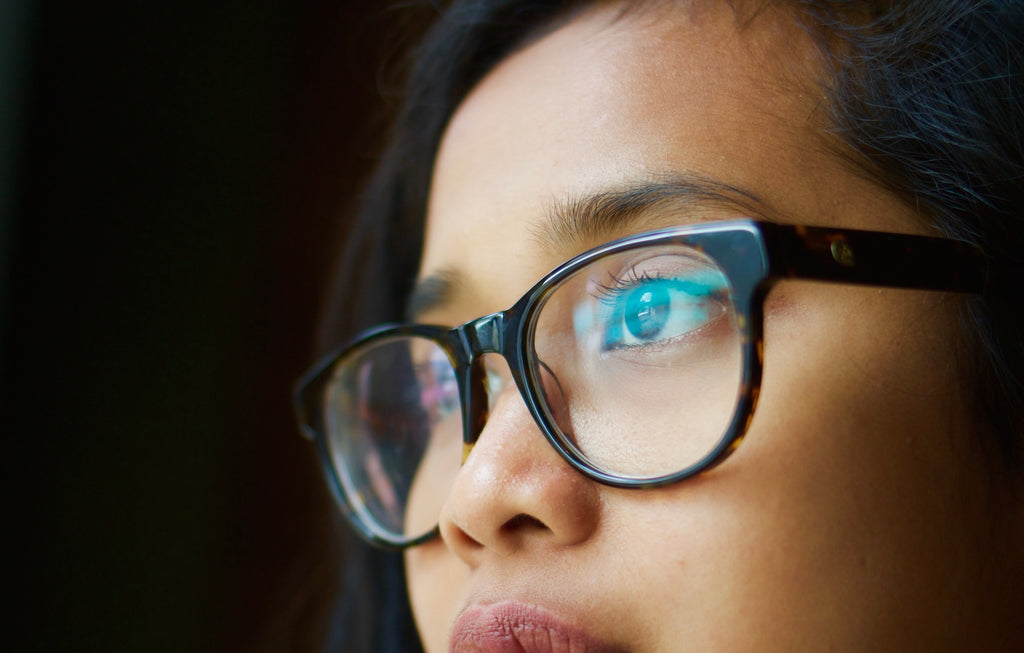 A girl with light reflecting on the surface of her glasses causing eyestrain.