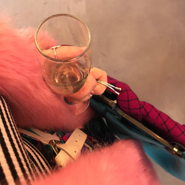 A woman carrying a glass of cava while shopping