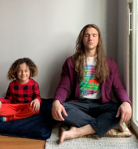 Father and son meditating, sitting side-by-side with legs crossed.