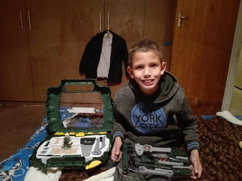 happy boy sitting on his bed with toy tool set