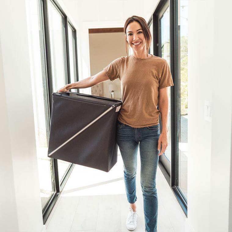 woman carrying a Quick Zip Hamper down the hall