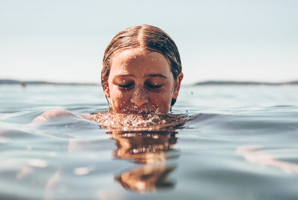 Woman with glowing skin swimming in water