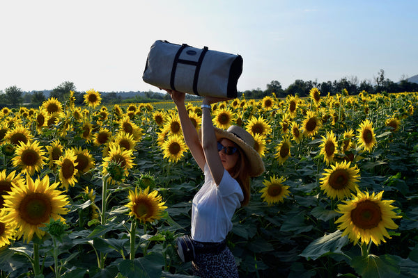 Vocco's Mediterraneo Weekender bag at a sunflowers field.