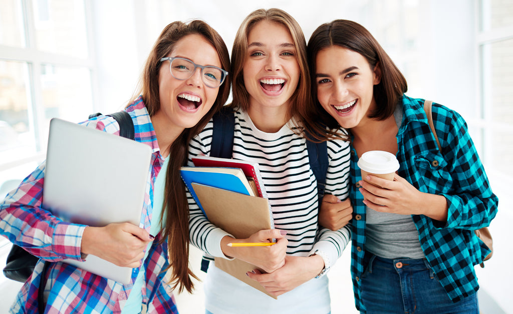 three smiling teen girls standing in hallway