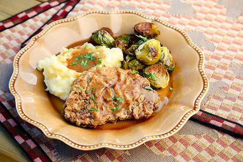 Image of plated chicken fried elk steak with mashed potatoes, brown gravy, and brussels sprouts.