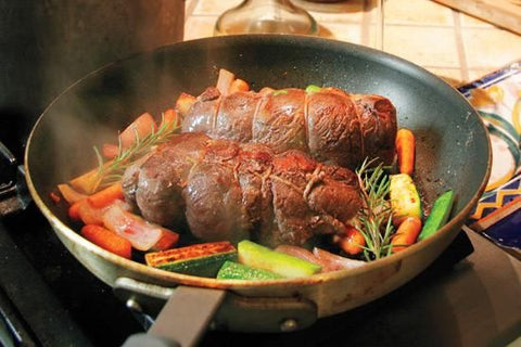 Image of stuffed goose medallions in a saute pan along with fresh vegetables.