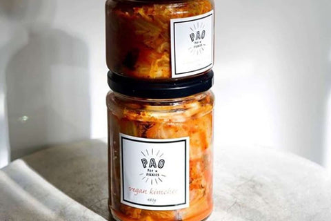 Two jars of kimchi with white labels on the front