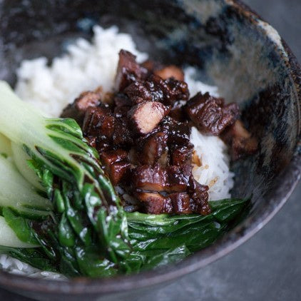 Pork slices in a bowl with rice and pak choi