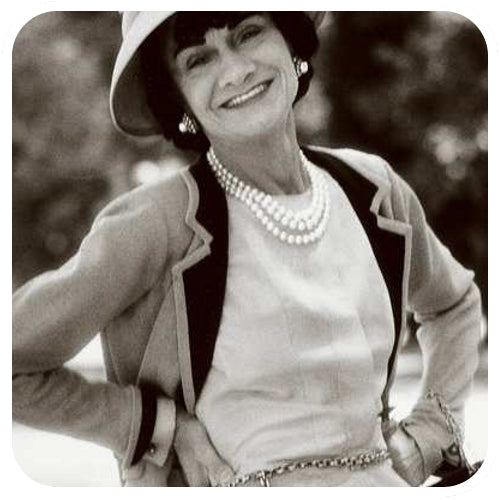 Coco Chanel wearing cufflinks on a white blouse, blazer and dress.