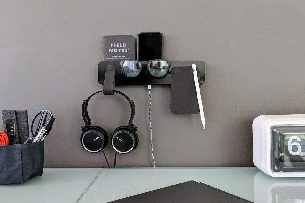 color coordinated wall mount organizer holding a notebook, headphones, sunglasses, phone, wallet, and stylus