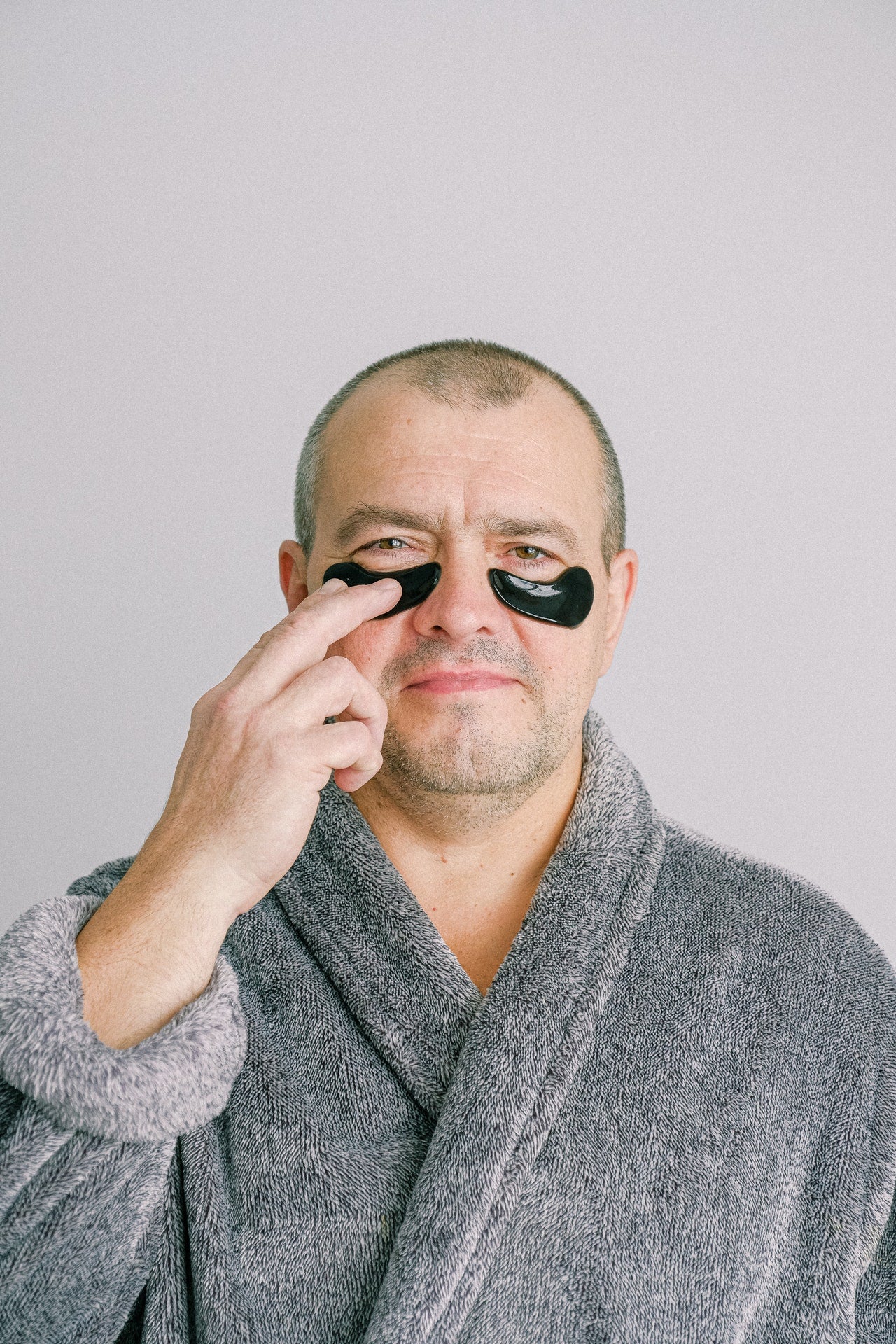Man in grey bathrob wearing under-eye patch