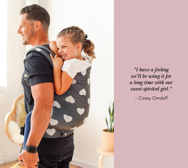 A father is carrying his Preschool daughter in back-carry position. Next to him is his quote.