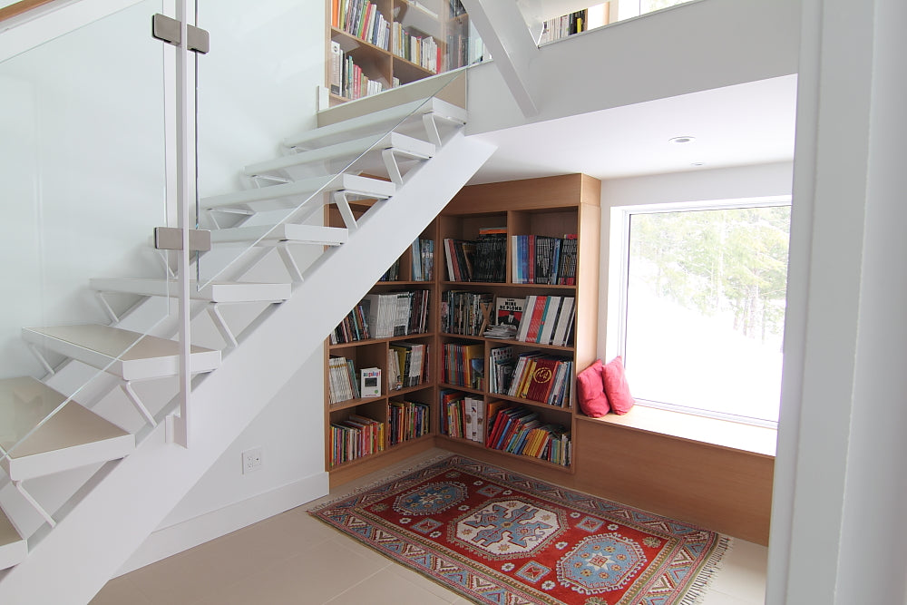 20 Creative Ideas To Use The Space Under Your Stairs - Hongkiat - One more home library under the stairs idea, this time with a comfortable  reading spot near the window sill.