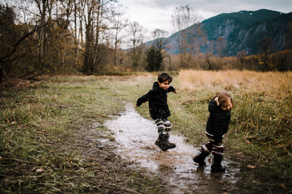 two kids playing in a puddle