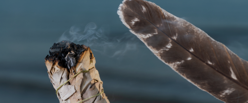 feather blowing burning sage to cleanse holistic skincare