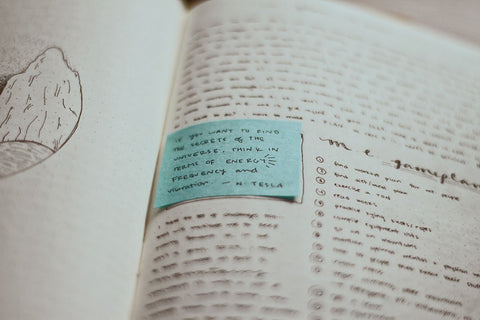 up close notebook with black ink writing and a blue sticky note