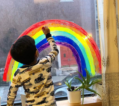 boy painting rainbow on window