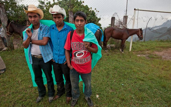 Three men standing near horses.