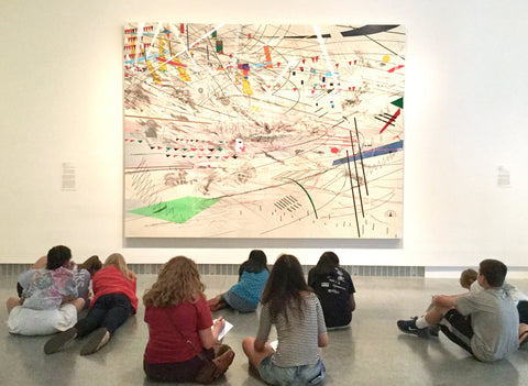 Students sitting in front of a large Julie Mehretu painting, with abstract shapes and lines