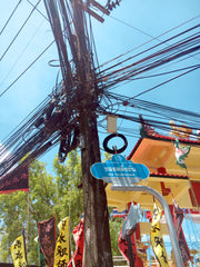 Tangled electric wires in a street scene from Phuket, Thailand with traditional buildings in the background