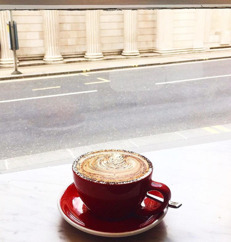 Grind cappuccino in red cup looking out to the street