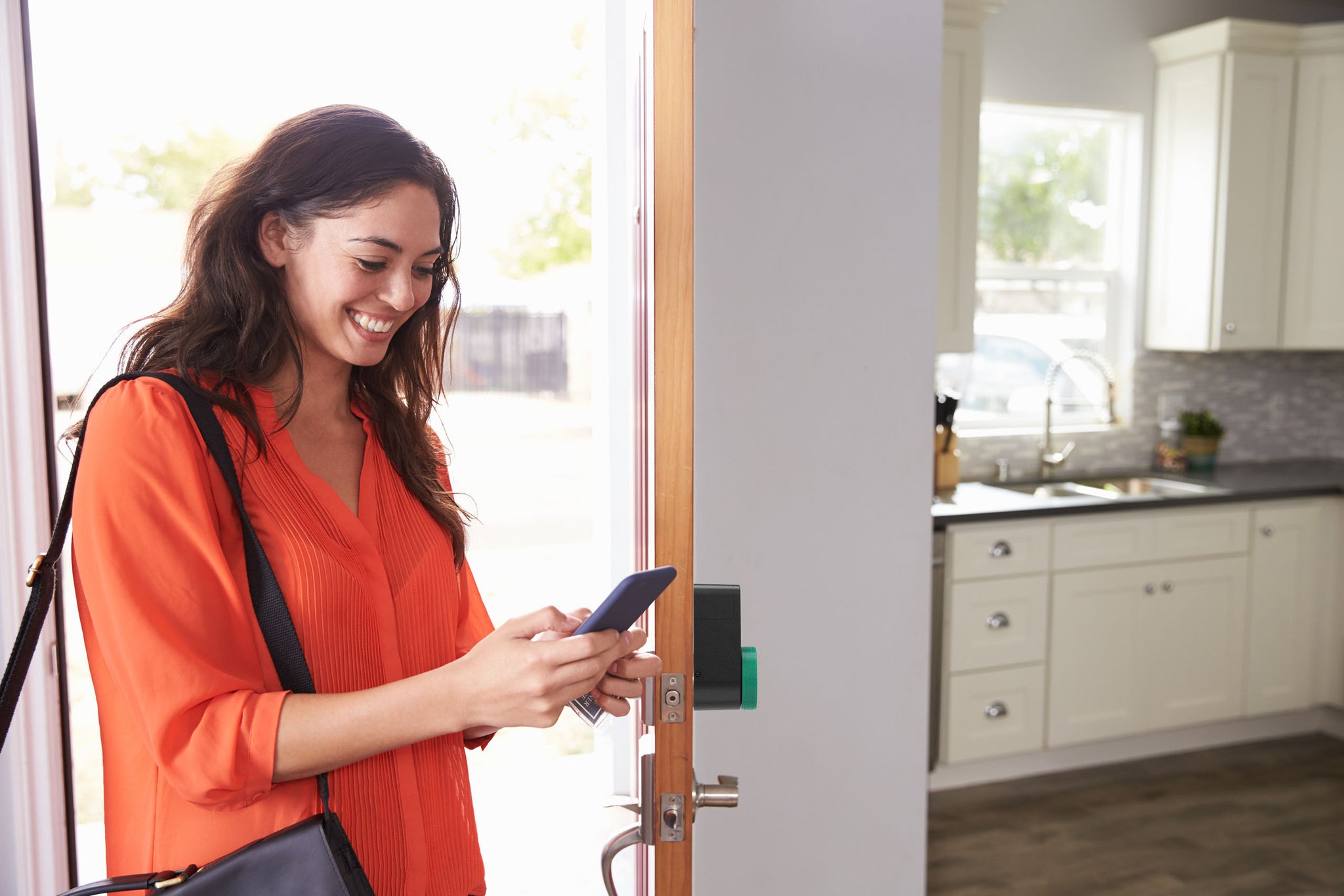 Girl entering the house using the smartphone and smart lock