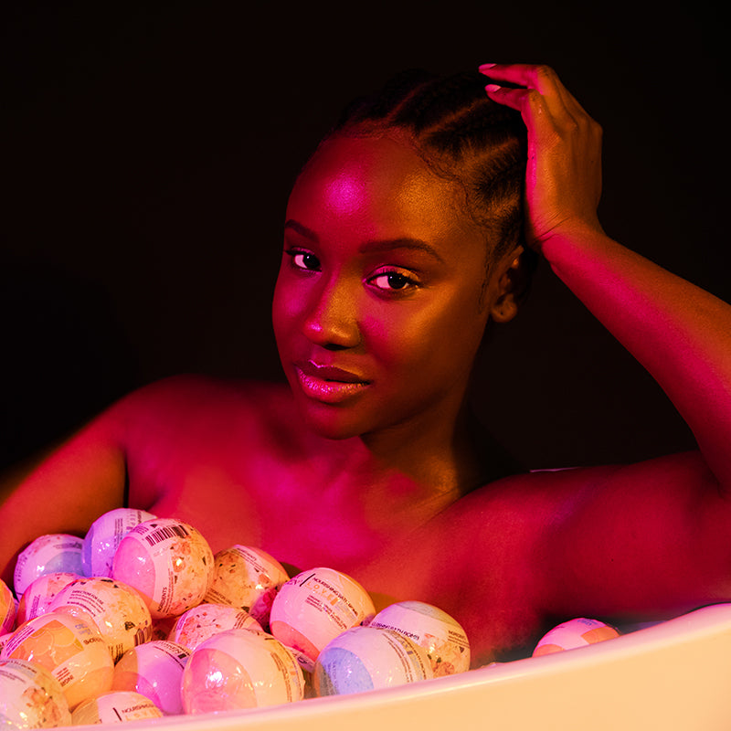 Joy Brunson modeling for Kush Queen CBD Bath Bombs, shown in a tub full of bath bombs.
