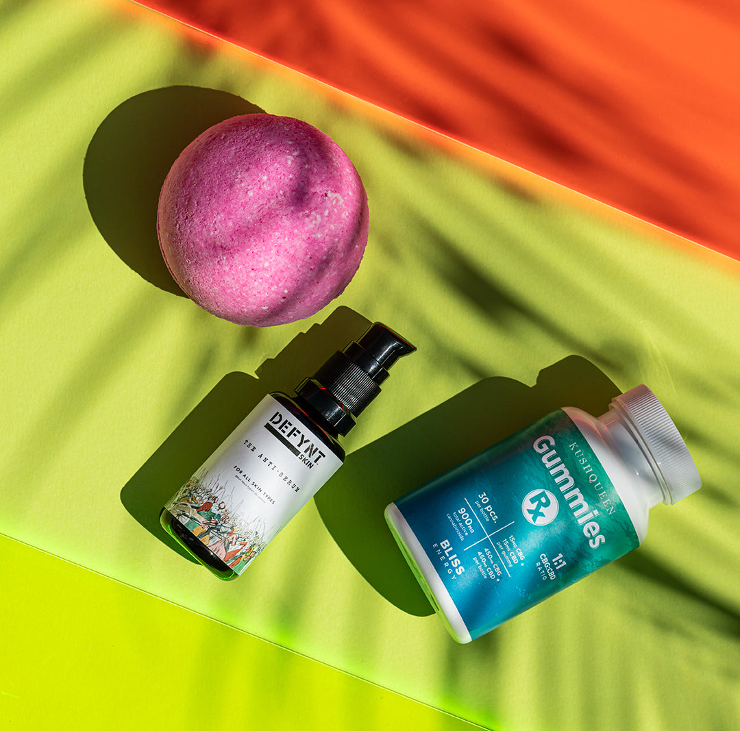 Kush Queen Awaken CBD Bath Bomb, Defynt CBD Skin Serum, and Gummies RX on a colorful summer backdrop.