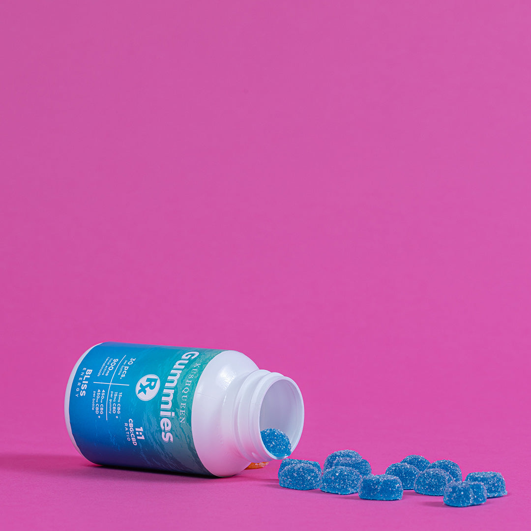 CBG+CBD Gummies Rx Bliss spilling out of the bottle against a pink background.