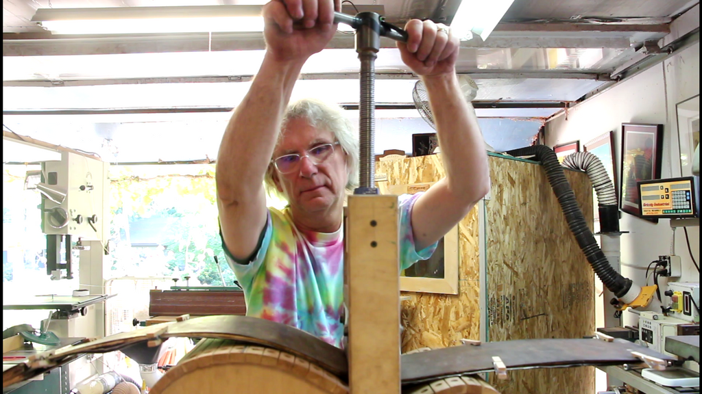 turning the main pressure bolt on the bending machine to bend wood for guitars