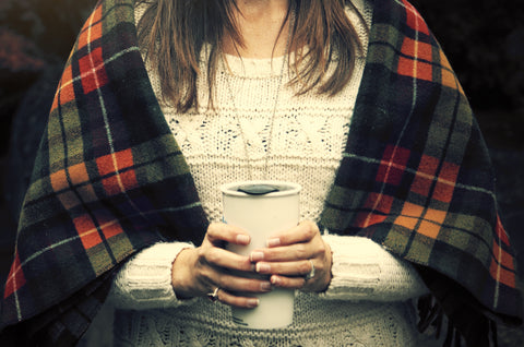 Woman holding reusable coffee mug