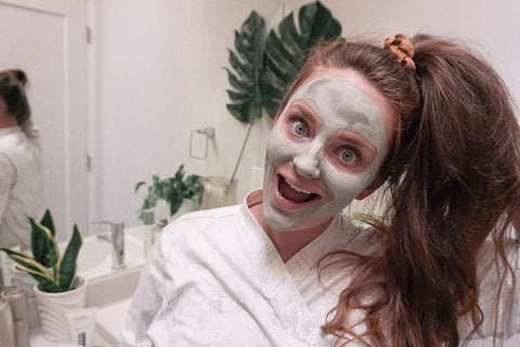 influencer woman in bathroom wearing a clay mask