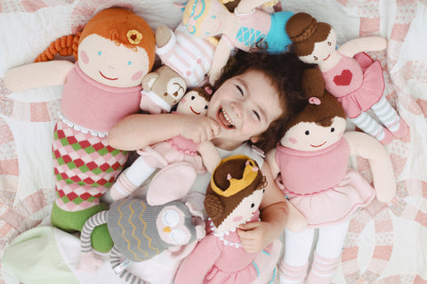 little girl smiling covered in knit Zubel toys