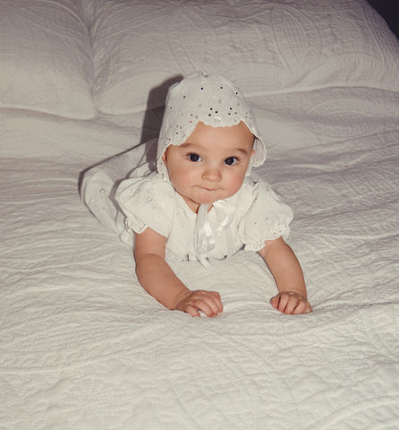 baby girl in white eyelet gown and bonnet 