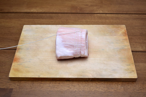 Wrapping and tying pork roll and working towards the opposite end