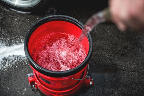 Filling up a car wash bucket with car before washing