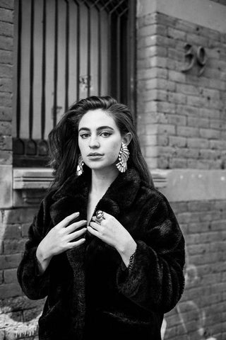 Aija Mayrock poses in a black furcoat with a striking avant-garde gold earring.
