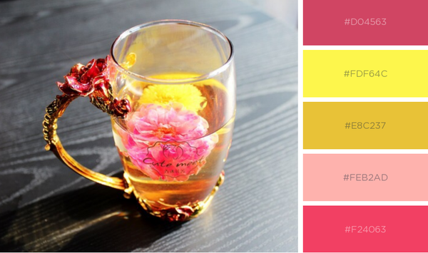 Glass cup of tea with pink and yellow flowers in it