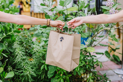 Two hands with a delivery bag in the middle. One person is handing to the other. 