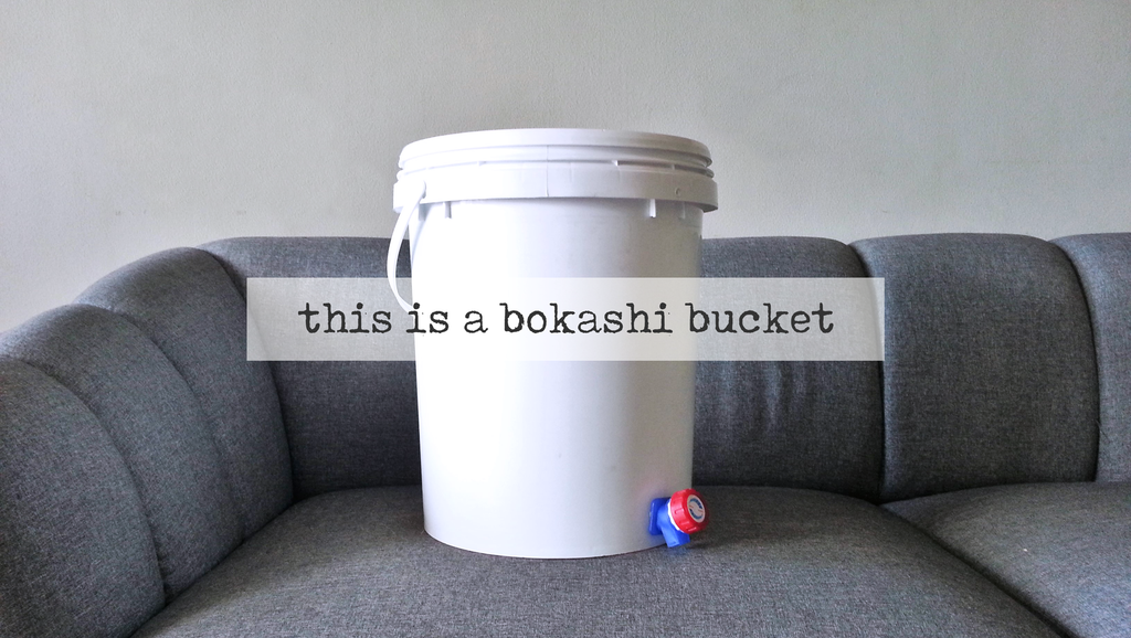 white bokashi bucket with faucet on grey surface