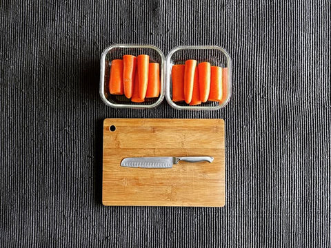 carrots-in-glass-containers-and-knife-on-wooden-bamboo-chopping-board
