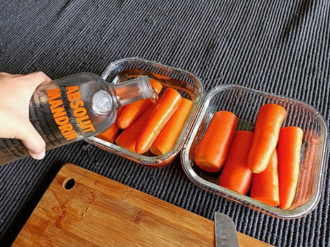 absolut-vodka-bottle-carrots-in-glass-containers-knife-on-wooden-bamboo-chopping-board