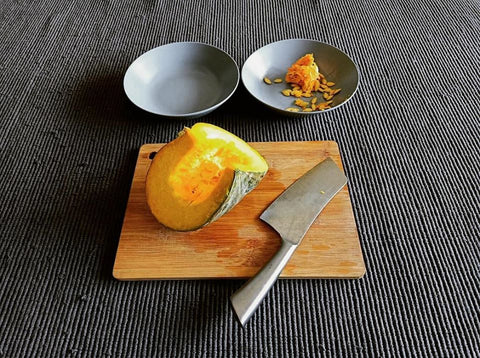 pumpkin-kalabasa-slices-and-knife-on-wooden-bamboo-chopping-board-squash-seeds-in-bowl