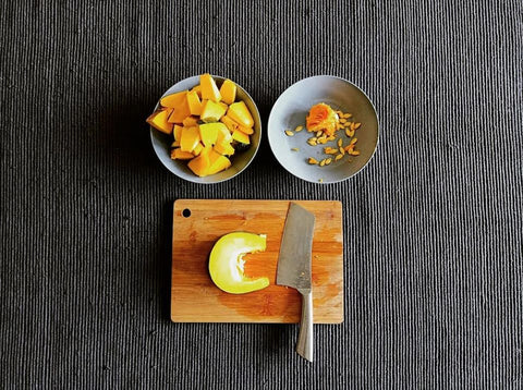 squash-pumpkin-kalabasa-slices-and seeds-in-bowls-and-knife-on-wooden-bamboo-chopping-board