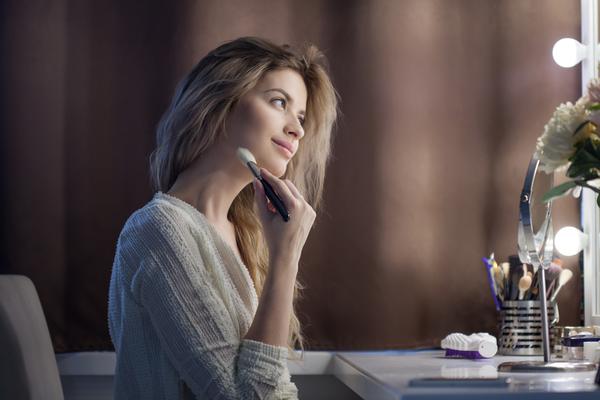 relaxed woman doing makeup in front of mirror