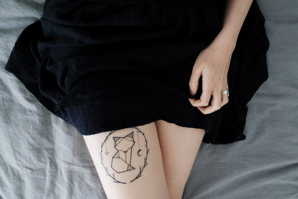 Girl with kitten tattoo laying on bed