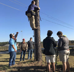 A person demonstrates to students the correct method for climbing a tree stand.