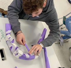 A student attempts to create a set of deer antlers using construction paper and tape.