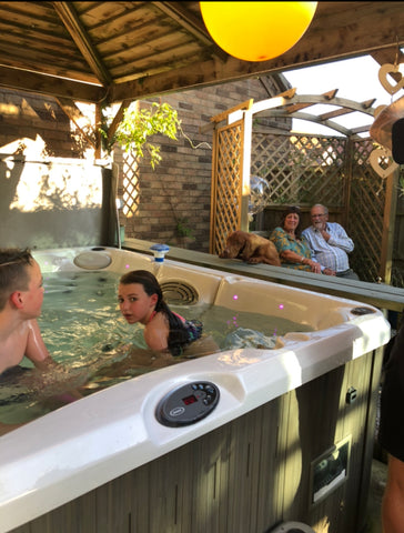 Gazebo covered hot tub surrounded by people and a dog