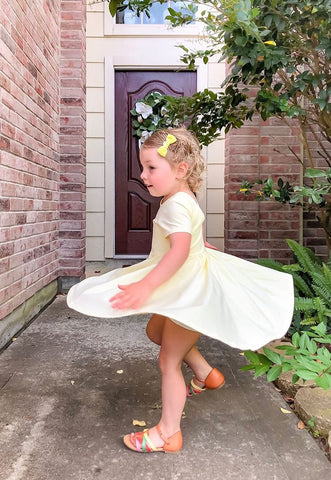 toddler in yellow twirl dress spinning around in front of her front door